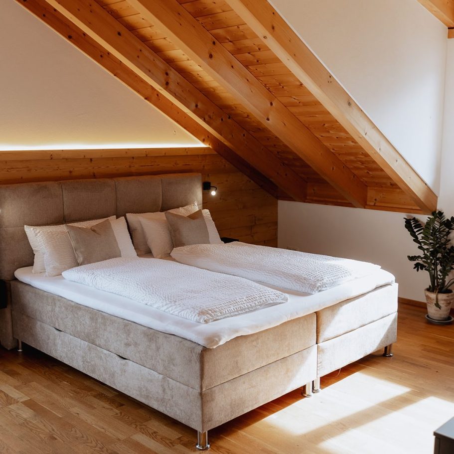Schlafzimmer Helles Schlafzimmer mit Doppelbett und Holzdetails unter einer schrägen Decke.